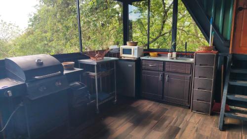 a kitchen with a stove and a microwave at Cocolhu Treehouse & Ocean View in Tamarindo
