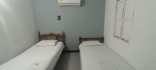 two beds in a small room with white walls at Casa Hotel La Unión in Santa Cruz de Mompox