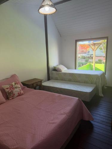 a bedroom with two beds and a window at Chalé Lunar in Arraial d'Ajuda