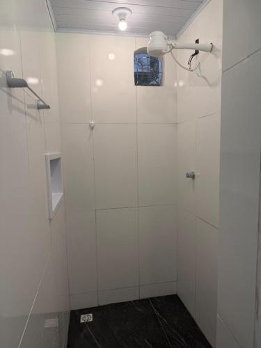 a bathroom with a shower with white walls and a window at Chalé Lunar in Arraial d'Ajuda