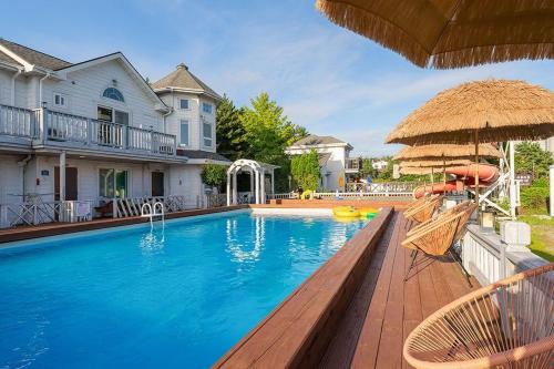 a swimming pool with chairs and an umbrella at Taean Modern186 Pension in Taean