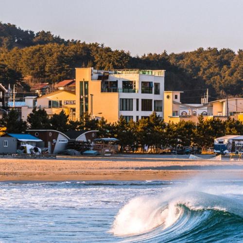 a wave in the ocean with a building in the background at Yangyang Hotel Unbound House in Yangyang