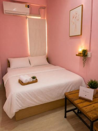 a small bedroom with a white bed and a table at Hostel In The City in Pom Prap