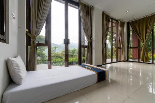 a large bed in a room with large windows at Barusen Hills By BHATARA in Gambung