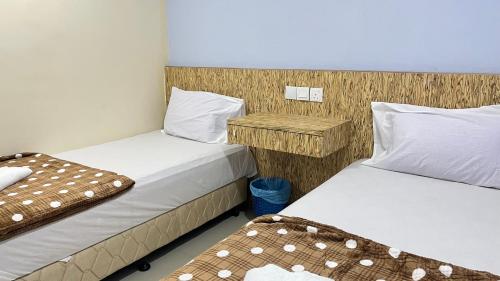 a room with two beds and a night stand at Winnieys Boutique Hotel in Kuala Lumpur