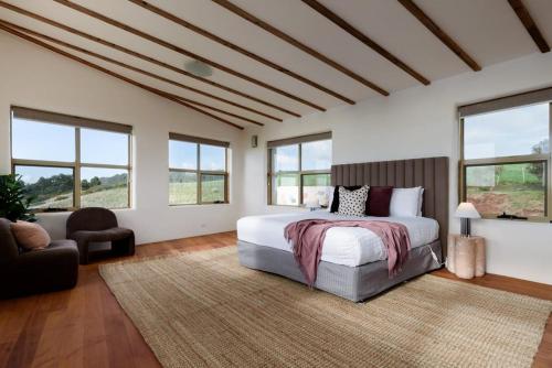 a bedroom with a large bed and windows at The Hemp House | Table Cape Ocean Views in Table Cape