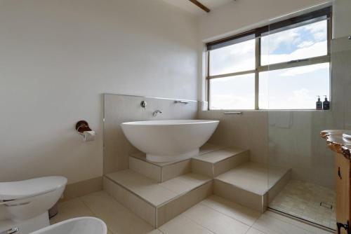 a bathroom with a sink and a toilet and a window at The Hemp House | Table Cape Ocean Views in Table Cape