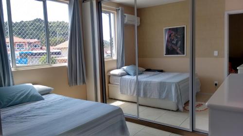 1 dormitorio con 2 camas y ventana grande en Apartamento Cachoeira do Bom Jesus, en Florianópolis