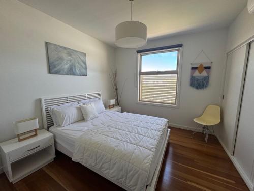 a bedroom with a white bed and a window at Amaroo by the beach in Queenscliff