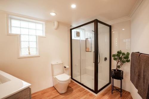 a bathroom with a toilet and a glass shower at Aurora in Queenscliff