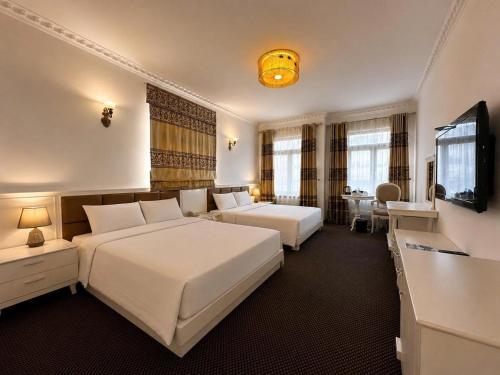 a hotel room with two beds and a flat screen tv at Luxor Boutique Hotel in Hanoi