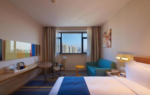 a hotel room with a bed and a chair at Holiday Inn Express Shanghai Zhenping by IHG in Shanghai