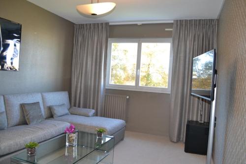 a living room with a couch and a glass table at Hôtel de Guyenne in Talence