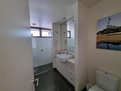 a white bathroom with a sink and a mirror at Beach Haven in Point Lonsdale