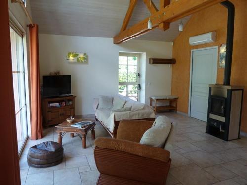 a living room with a couch and a tv at Au Bas Chalonge in Ligné