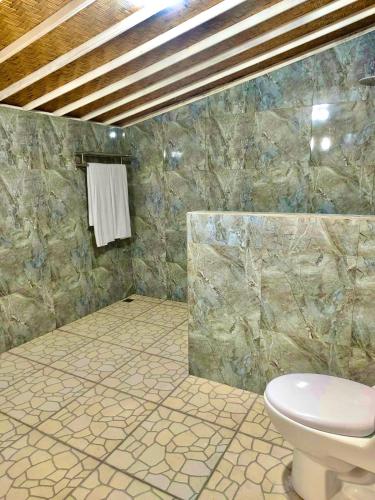 a bathroom with a toilet and a stone wall at Jalana Palm Villa in Tabanan