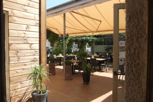 a patio with tables and chairs under a tent at Hôtel U Pozzu in Sisco
