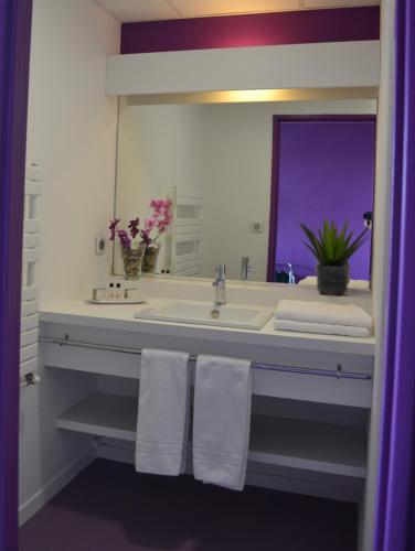 een badkamer met een wastafel, een spiegel en handdoeken bij Hôtel de Guyenne in Talence