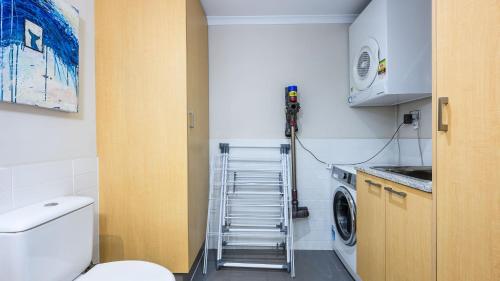 a bathroom with a toilet and a washing machine at Del Mar 1 in Mandurah
