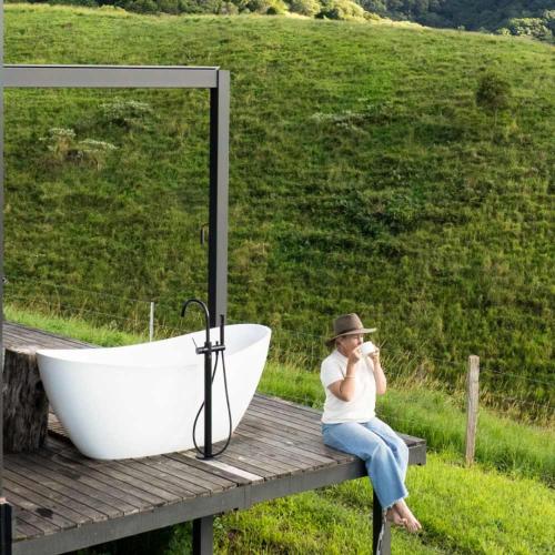 a woman sitting on a bench next to a bath tub at Aahana in Pinbarren