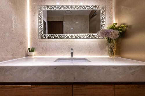 a bathroom sink with a mirror and a vase of flowers at New Cheonji Hotel in Seoul