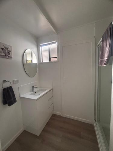 a white bathroom with a sink and a mirror at Pioneer Caravan Park in Dalby