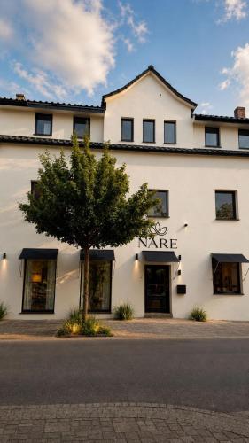 a white building with a tree in front of it at Hotel Nare in Boppard