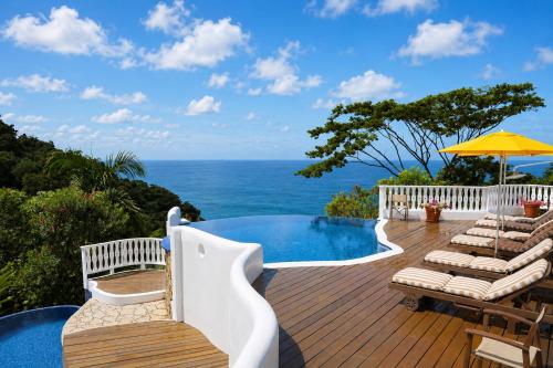 a deck with chairs and a pool and the ocean at Mount Edgecombe Boutique Hotel in Maran