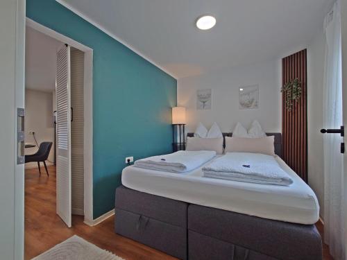 a bedroom with a large bed with a blue wall at JIRVISTA-Homes, voll ausgestattete Wohnung im EG, kontaktloser Zutritt in Burghausen