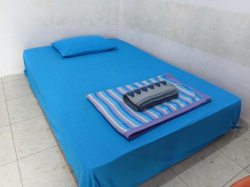 a blue bed with a blue pillow and a comb at Wale Chika Guest House in Tomohon