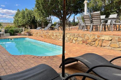 a swimming pool with chairs and an umbrella at Peace Valley Guesthouse in Napier