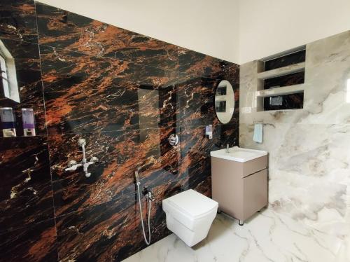 a bathroom with a toilet and a marble wall at Dheer- BnB at an Artist's Abode in Shānti Niketan