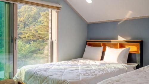 a bedroom with a bed and a large window at Gapyeong The Hill Pool Villa in Gapyeong