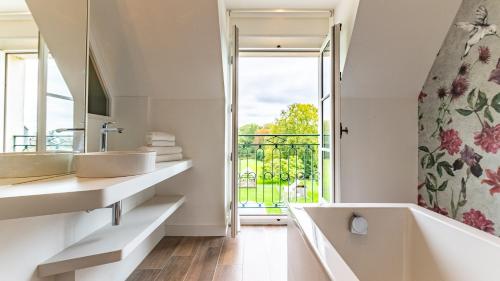 a bathroom with two sinks and a tub and a window at Château de Saulon in Saulon-la-Rue