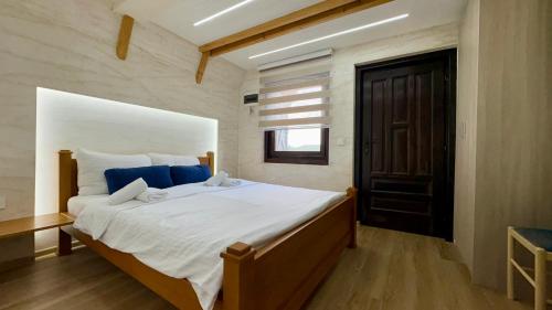 a bedroom with a large white bed with blue pillows at OSTROG Aparthotel KOLIBA-VLASTNIŠTVO MANASTIRA OSTROG in Nikšić