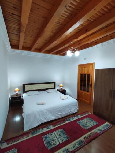 a bedroom with a white bed and a wooden ceiling at Golden Minaret with Terrace in Bukhara