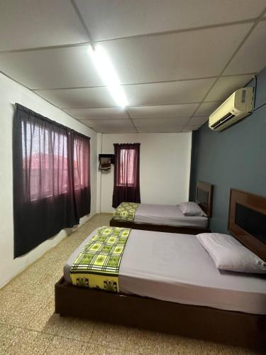 two beds in a room with two windows at planet hotel mersing in Mersing