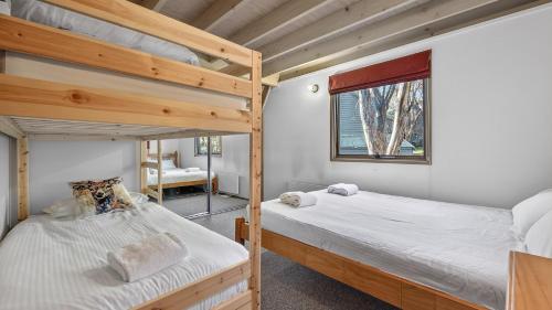 two bunk beds in a room with a window at Coho in Dinner Plain