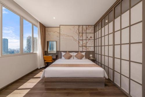 a bedroom with a large bed and large windows at Petro Hotel Da Nang in Danang