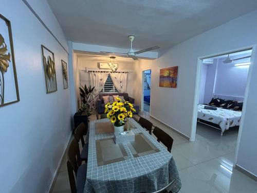 a dining room with a table with yellow flowers on it at D'Nas Homestay in Rawang