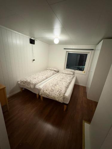 zwei Betten in einem kleinen Zimmer mit Fenster in der Unterkunft Ravnklo in Sørkjosen
