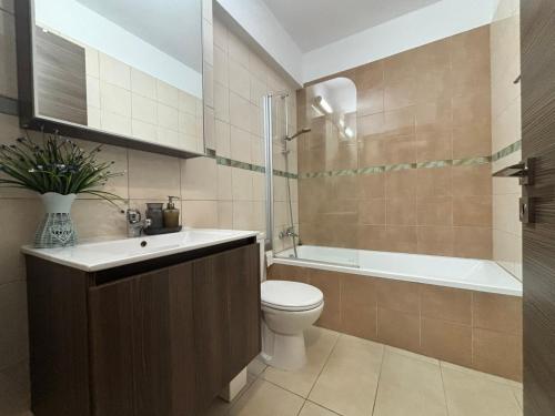 a bathroom with a toilet and a sink and a tub at Domino Blue Apartment in Paralimni