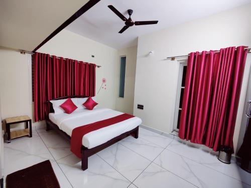 a bedroom with a bed with red curtains and a ceiling fan at Mysore Studio Rooms in Mysore