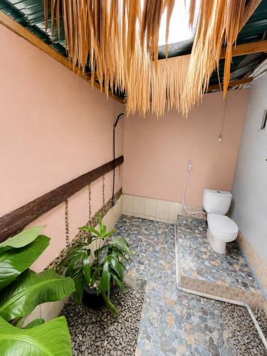 a bathroom with a toilet and some plants at Jungle life guesthouse Trekking & Transport Book with us in Bukit Lawang