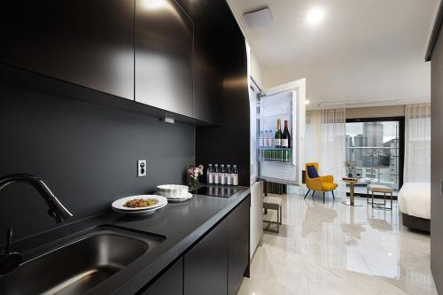 a black kitchen with a sink and a dining room at Busan Yeongmu Parade Hotel Haeundae Beach in Busan