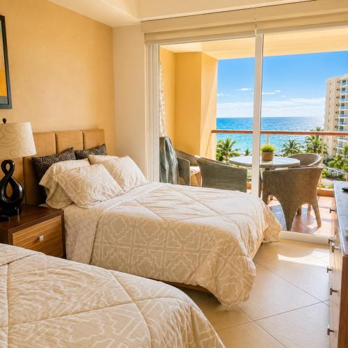 two beds in a bedroom with a view of the ocean at Luxury Beachfront Condo at Del Canto Residences - Amazing Views! in Nuevo Vallarta