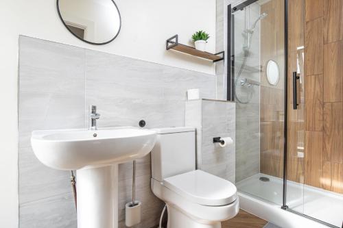 a bathroom with a sink and a toilet and a shower at 5 Bedroom House in Ashton-under-lyne with Free Parking and Easy Access to City Centre in Stalybridge