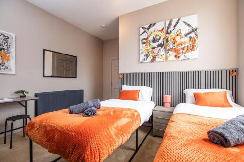 a bedroom with two beds with orange sheets at 5 Bedroom House in Ashton-under-lyne with Free Parking and Easy Access to City Centre in Stalybridge