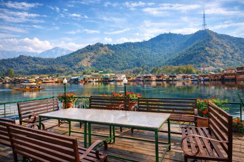 a table and chairs on a deck with a view of a lake at Heritage Amina Group Of Houseboats in Srinagar