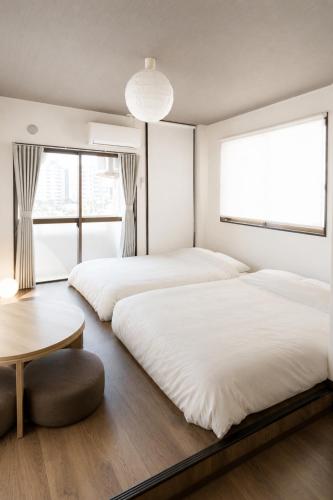 two beds in a room with a table and windows at Bears Building in Kumamoto
